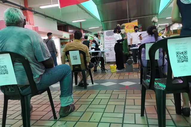 Distanced waiting chairs with Remedine flyers at a free health screening in Pasar Besar TTDI