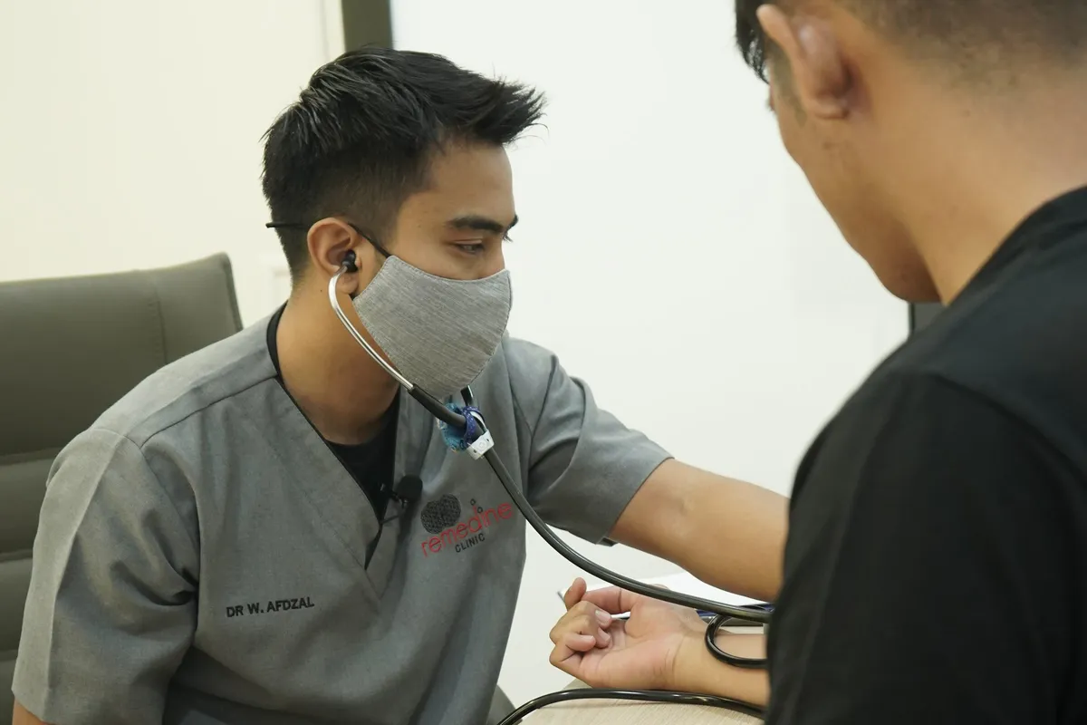 Dr Wan Afdzal taking a patient's blood pressure at Remedine Clinic