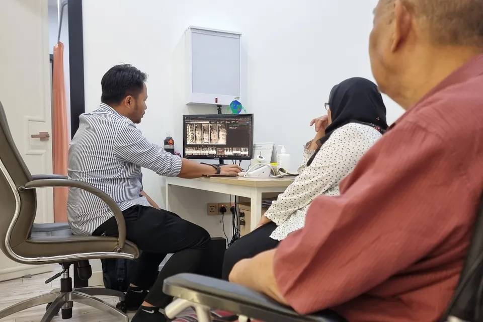 A senior patient and family reviewing scans with the doctor in a consultation room