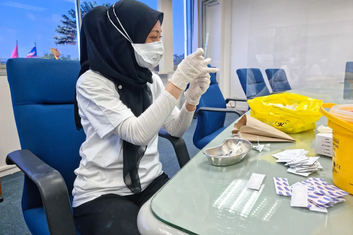 Remedine nurse preparing a vaccine at an onsite clinic session